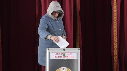 Eine Frau wirft ihren Wahlzettel in eine Urne.