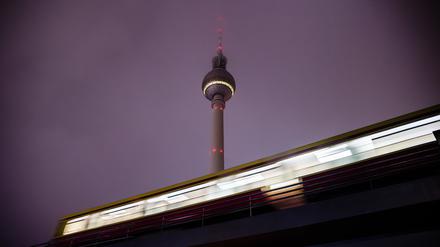 Eine S-Bahn fährt am Morgen vor dem Berliner Fernsehturm aus dem Bahnhof Alexanderplatz. (Bewegungsunschärfe durch lange Belichtungszeit)