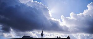 Die Sonnenstrahlen kommen hinter einer dunklen Wolke über dem Berliner Fernsehturm hervor. 