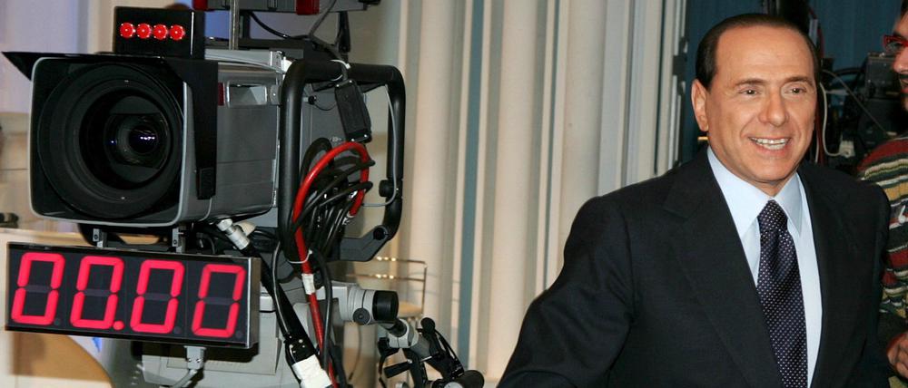 Silvio Berlusconi steht während einer TV-Produktion neben einer Fernsehkamera (Archivfoto vom 08.03.2006). Der italienische Medienkonzern MFE-Mediaforeurope hält inzwischen 28,9 Prozent an ProSiebenSat.1. 