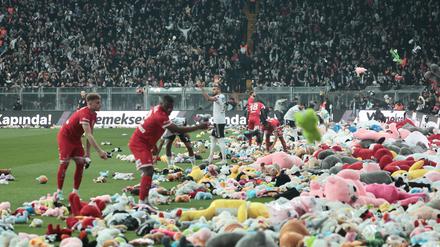 Fußballfans werfen Stofftiere als Zeichen der Solidarität auf den Rasen. 