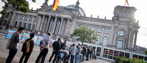 ARCHIV - 03.09.2023, Berlin: Menschen stehen am Reichstagsgebäude des Deutschen Bundestages vor den provisorischen Gebäuden zur Besucherkontrolle. (zu dpa: «Bauplan für Besucherzentrum am Bundestag fertig») Foto: Fabian Sommer/dpa +++ dpa-Bildfunk +++