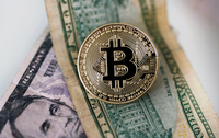 Archivbild einer Bitcoin Münze, die auf einem Dollar Geldscheinen liegt (gestellte Szene).