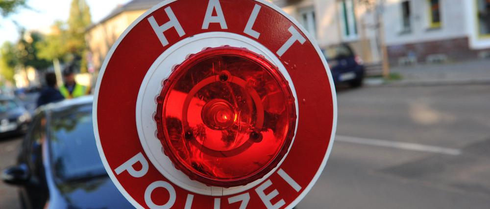 Ein Polizist stoppt in Berlin mit einer Kelle ein Auto. (Symbolbild)
