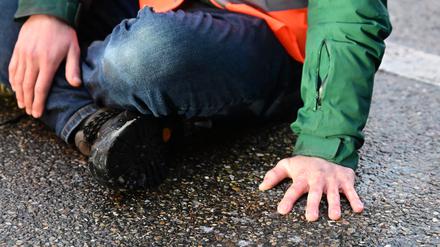 Ein Aktivist hat sich mit einer Hand auf einer Straße festgeklebt. 