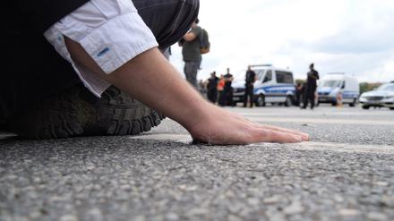 Ein Klimaaktivist hat sich mit der Handfläche am Asphalt einer Straße festgeklebt. 