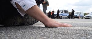 Ein Klimaaktivist hat sich mit der Handfläche am Asphalt einer Straße festgeklebt. 