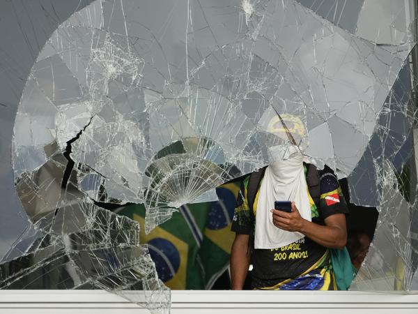 Ein Mann blickt aus einem zerbrochenen Fenster des Palacio do Planalto, den offiziellen Sitz des brasilianischen Präsidenten.