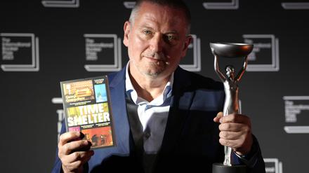 Georgi Gospodinow (l.), Schriftsteller aus Bulgarien, hält die Siegertrophäe hoch, nachdem sein Buch „Time Shelter“, den International Booker Prize 2023 gewonnen hat.