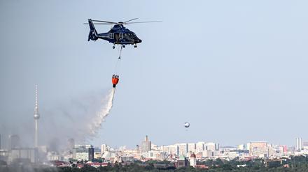 Ein Hubschrauber der Bundespolizei wirft Wasser über der Brandstelle im Grunewald ab. 