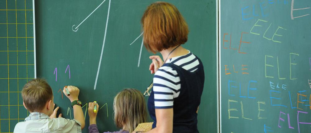 Ein rechtshändiger Junge und ein linkshändiges Mädchen der ersten Klasse einer Grundschule im Unterricht.