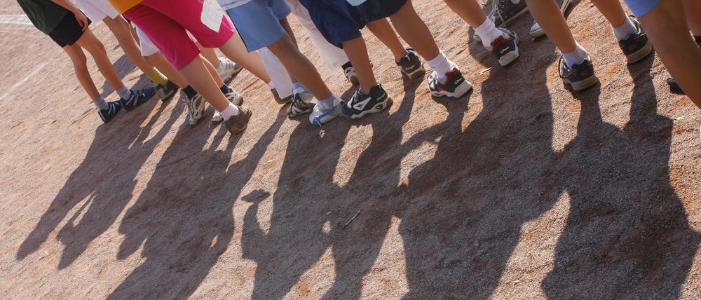 Kinder einer Grundschule stehen bei einer Veranstaltung im Rahmen der Bundesjugendspiele auf einem Sportplatz.