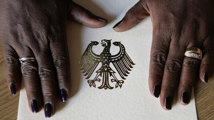 Die Hände einer Frau liegen auf der Einbürgerungsurkunde der Bundesrepublik Deutschland.