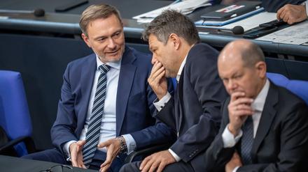 Bundeskanzler Olaf Scholz (SPD, r), verfolgt neben Robert Habeck (Bündnis 90/Die Grünen, M), Bundesminister für Wirtschaft und Klimaschutz, und Christian Lindner (FDP), Bundesminister der Finanzen, die Debatte nach einer Regierungserklärung zur Haushaltslage im Bundestag. 