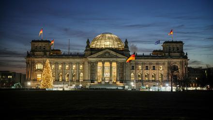 Das Reichstagsgebäude mit dem Bundestag wird am Morgen in der blauen Stunden angestrahlt.