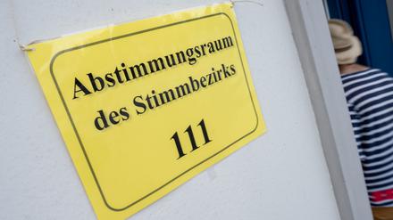 Ein Schild mit dem Schriftzug «Abstimmungsraum des Stimmbezirks 111» hängt am Eingang eines Abstimmungsraums.