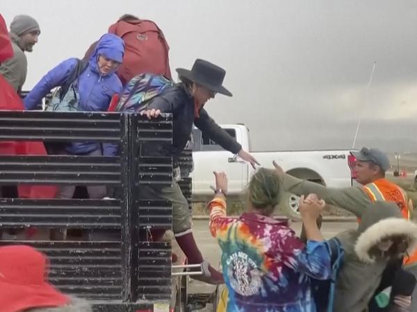 Aufbruch aus der Wüste: Festivalbesucher werden mit einem Lastwagen vom Gelände gebracht. 