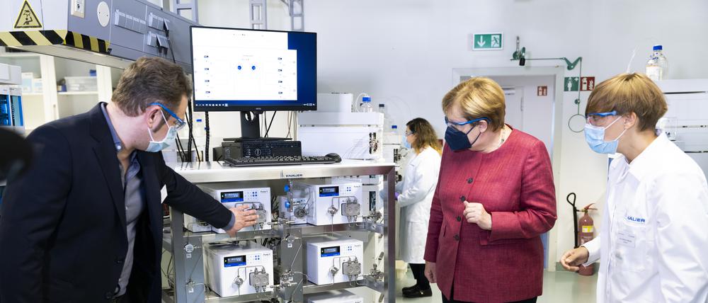Knauer-Geschäftsführer Carsten Losch und Kate Monks, Leiterin Applikationen, Akademie & Qualität erläutern Angela Merkel ein IJM-Skid zur Lipid-Nanopartikelherstellung für mRNA-Impfstoffe.
