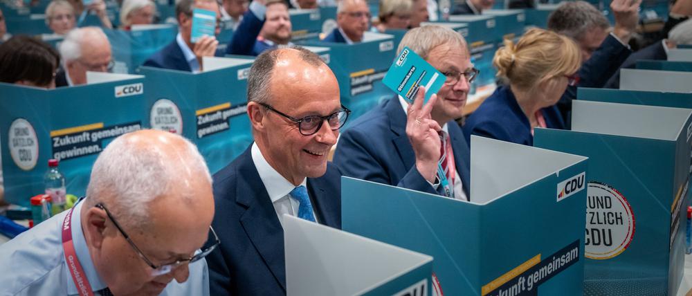 Der CDU-Vorsitzende Friedrich Merz sitzt beim Bundesparteitag bei der Wahl zwischen den Delegierten. 