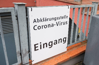 Schild an Zaun mit der Aufschrift: Abklärungsstelle Corona-Virus, Eingang.