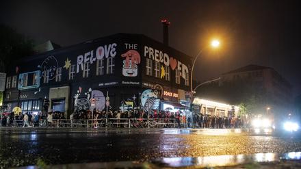 Menschen stehen im strömenden Regen dicht an dicht am Eingang zum Kitkat-Club.