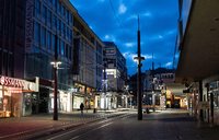 Ein Mann geht in der sogenannten blauen Stunde in Witten an den Geschäften in der ansonsten leeren Fußgängerzone vorbei.