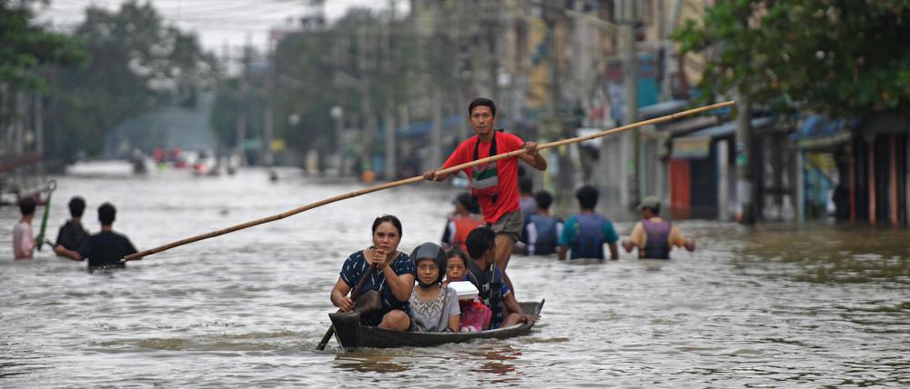Anwohner bahnen sich einen Weg durch eine überschwemmte Straße nach schweren Regenfällen in der Stadt Bago  in Myanmar am 9. Oktober 2023.