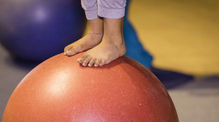 Ein Kind balanciert auf einem Gymnastikball.