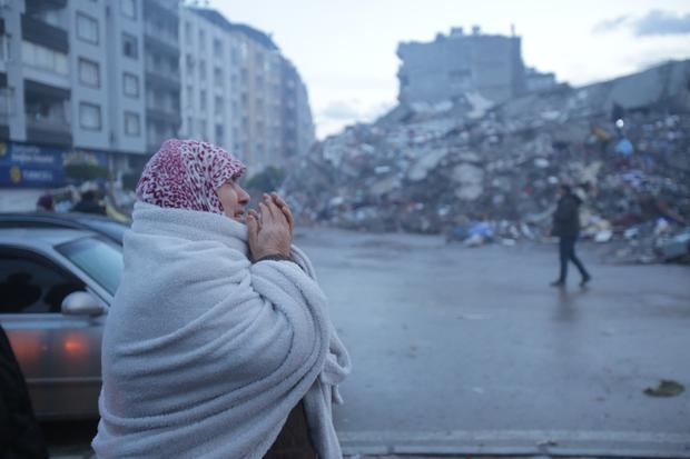 Eine Frau im Bezirk Iskenderun in Hatay, einer der am stärksten von den Erdbeben in der Türkei betroffenen Städte. Viele Menschen verbrachten die Nacht bei regnerischem, kaltem Wetter im Freien und verbrannten Brennholz, um sich warmzuhalten. 