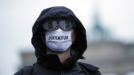 Ein Teilnehmer einer Demonstration gegen die Corona-Einschränkungen der Bundesregierung trägt eine Mund-Nasen-Bedeckung mit der Aufschrift „Diktatur“. 