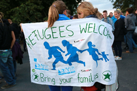 Zwei junge Frauen sind in ein Banner mit der Aufschrift Refugees welcome gehüllt.