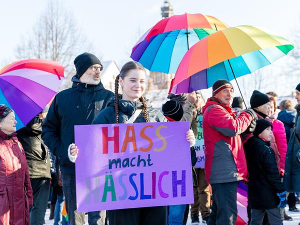 20.01.2024, Brandenburg, Spremberg: Menschen halten Schirme in Regenbogenfarben bei der Demonstration «Bunte Zukunft statt braunes Hinterland». Ein Mädchen hält dabei ein Schild mit der Aufschrift „Hass macht hässlich“.