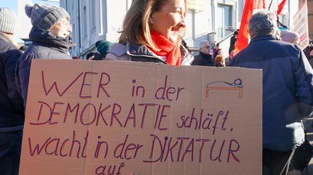 Thüringen, Gera: Eine Demonstrantin hält ein Plakat mit der Aufschrift «wer in der Demokratie schläft, wacht in derr Diktatur auf» während einer Kundgebung und Demonstration unter dem Motto «Für ein weltoffenes Thüringen - Gegen faschistische Paktierereien».