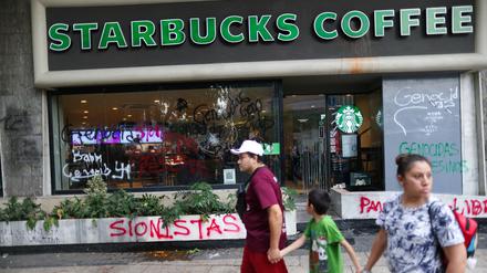 Vandalismus in Mexiko City. Passanten gehen an einem von Demonstranten beschmierten Café von Starbucks vorbei.  