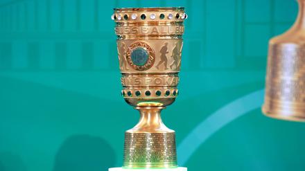 Der DFB-Pokal steht vor einer türkisen Leinwand.