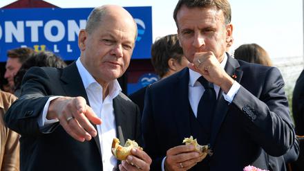 Bundeskanzler Olaf Scholz (SPD, links) und Frankreichs Präsident Emmanuel Macron essen 2023 gemeinsam in Blankenese an der Elbe ein Fischbrötchen.