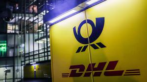 03.05.2024, Nordrhein-Westfalen, Bonn: Die Logos von Deutsche Post und DHL hängen am Posttower an einer Packstation. Die Deutsche Post AG hält ihre Hauptversammlung ab. Die Firma hat sich in DHL umbenannt, außer an der Börse, dort heißt sie weiterhin Deutsche Post AG. Foto: Oliver Berg/dpa +++ dpa-Bildfunk +++