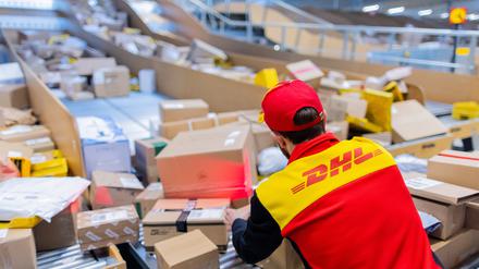 Ein Paketzusteller sortiert und räumt in einer Zustellbasis von Deutsche Post DHL in Nordhrein-Westfalen Pakete in ein Zustellfahrzeug. (Symbolbild)