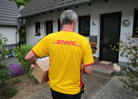 Ein DHL-Paketzusteller der Deutschen Post liefert in Königswinter (Nordrhein-Westfalen).