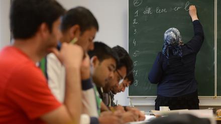 Eine Schülerin schreibt beim Deutschunterricht für Asylbewerber auf die Tafel. 