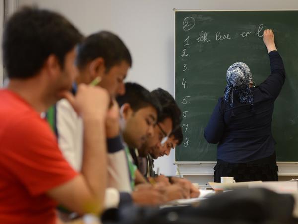 Eine Schülerin schreibt beim Deutschunterricht für Asylbewerber auf die Tafel. 