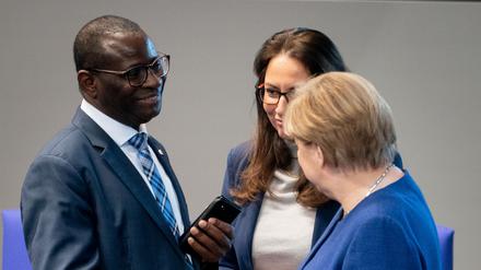Bundeskanzlerin Angela Merkel (CDU, r) unterhält sich bei der Sitzung des Bundestages mit den SPD-Bundestagsabgeordneten Karamba Diaby und Yasmin Fahimi.