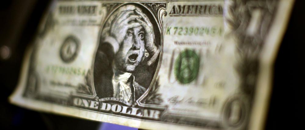 Eine Karikatur einer US-Dollar-Note mit dem Abbild George Washingtons, der sich die Hände über den Kopf zusammenschlägt, in der Börse in Frankfurt am Main an einem Monitor (Archivbild).