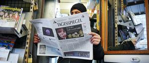 Ein Mitarbeiter schaut an seinem Kiosk in die Zeitung „Tagesspiegel“ im neuen Tabloid-Format. 