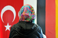 Eine Frau sitzt in der Ditib-Moschee im hessischen Friedberg vor einer türkischen und einer deutschen Fahne.