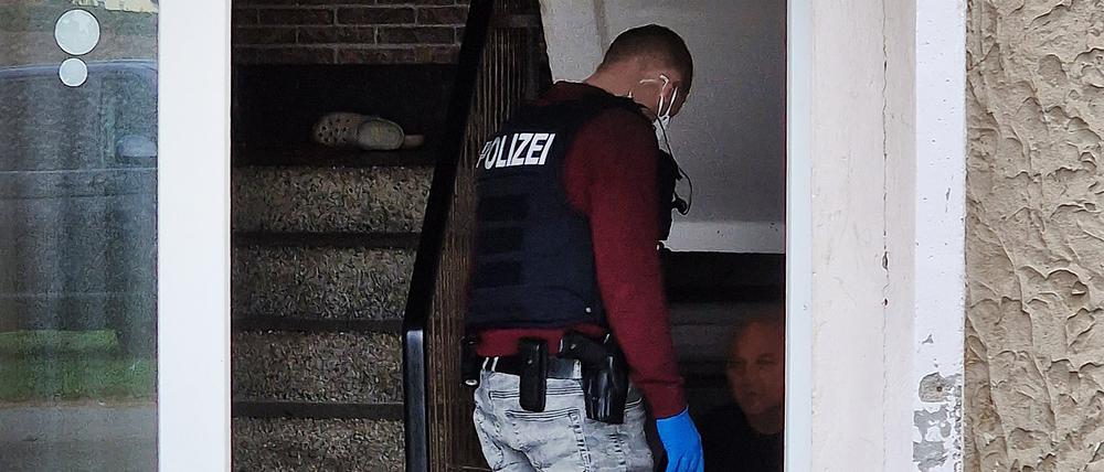 Ein Polizeibeamte geht während der Razzia in Straußfurt in einen Hauseingang.