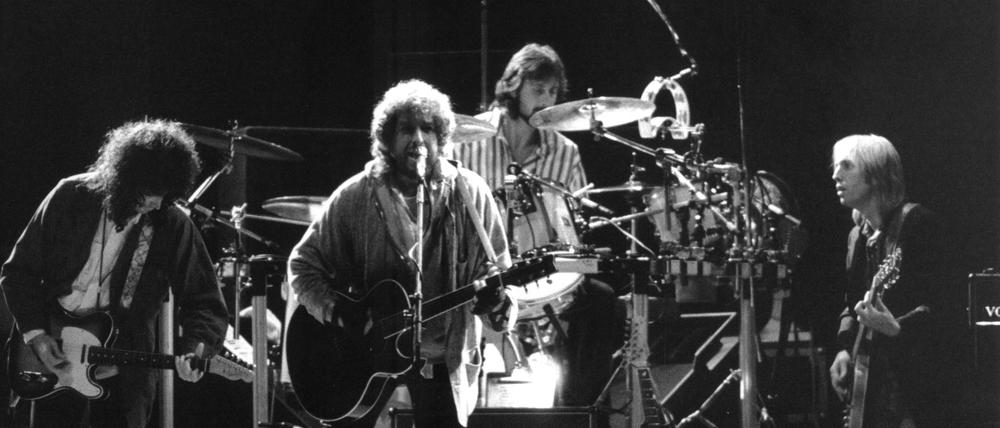 Der amerikanische Rockpoet Bob Dylan (M) und der US-Rockmusiker und Gitarrist Tom Petty (r) mit seiner Band "Heartbreakers" begeistern am 17. September 1987 die Zuschauer beim Friedenskonzert des DDR-Jugendverbandes "Freie Deutsche Jugend" (FDJ) auf der Treptower Festwiese in Berlin mit ihren Songs.