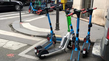 E-Scooter von drei verschiedenen Anbietern stehen auf einem dafür vorgesehenen Parkplatz in Paris.