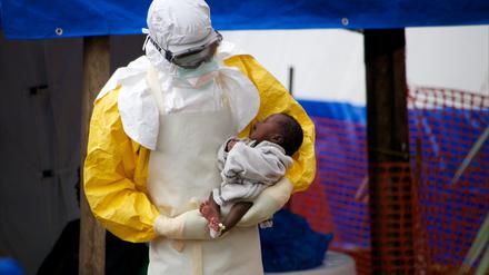 Ein möglicherweise mit Ebola infiziertes, zwei Wochen altes Kind wird im Osten von Guinea in einem Behandlungszentrum von einem Arzt auf dem Arm gehalten.