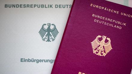Eine Einbürgerungsurkunde der Bundesrepublik Deutschland und ein deutscher Reisepass liegen auf einem Tisch.  